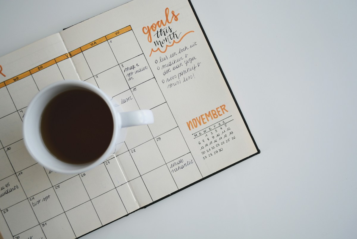 Coffee cup beside a paper planner; illustrative stock photograph