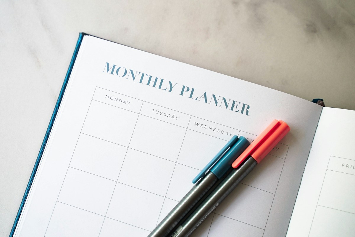 Paper planner and pens for organizing work; illustrative stock photograph